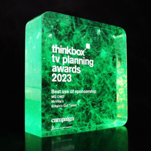 A translucent green recognition award with internal intricate patterns, illuminated from below. text on the award includes "thinkbox tv planning awards 2023", "best use of sponsorship", and other details.