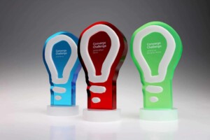 Recognition Awards Converge Challenge Three colorful converge challenge recognition awards stand in a row, each featuring a unique light bulb design in blue, red, and green, denoting different award categories.