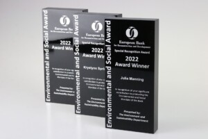 Three black acrylic recognition awards displaying the "european bank for reconstruction and development 2022 award winner" for different categories, standing upright on a gray surface.