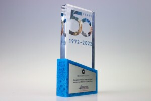 Clear acrylic recognition award with blue base commemorating "50 years 1972-2022". front features a collage of images within the number "50" and a congratulatory plaque from michigan lottery.
