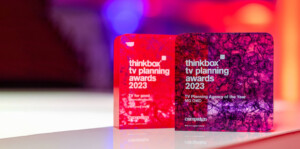 The Thinkbox TV Awards held at One Marylebone Road, 12th July 2023Photography by Fergus Burnett Two vibrant recognition awards from the thinkbox tv planning awards 2023 are displayed against a red and purple blurred background. the left award is red, and the right displays a detailed purple design.