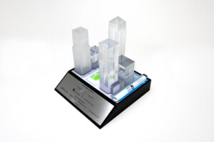 Scale model deal toys of a Canary Wharf displayed on a base with an informational plaque, against a white background.