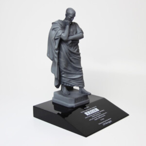 A deal toys statue of a contemplative figure, draped in a robe and resting its chin on a hand, displayed on a black pedestal labeled "ovidius" and "dior.