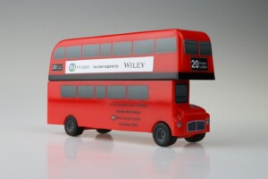A red double-decker bus deal toys model displaying logos and text indicating "hindawi has been acquired by wiley" and "scale to market with analytics." the bus is marked "20 project london.