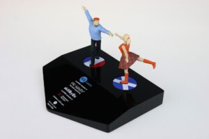 Two figurines of an elderly couple dancing atop a black deal toys platform labeled "primary health network," symbolising vitality and playfulness in aging.