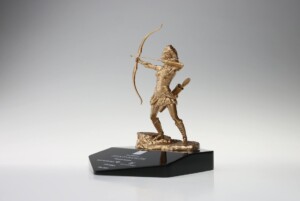 A bronze deal toys statue of an archer in dynamic pose, positioned on a black pedestal with inscriptions, set against a gradient gray background.