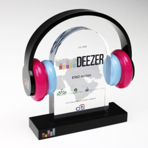 Deal toys featuring a clear glass plaque with multicolored country outlines and text, flanked by a large black arch and vibrant pink and blue headphones on the sides.