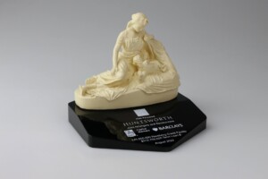 Porcelain figurine depicting a romantic scene of two individuals, mounted on a black base with a plaque indicating it is part of the "huntsworth collection by Barclays.