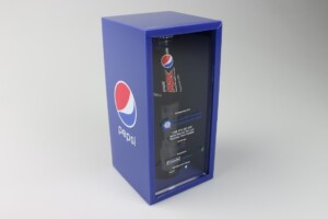 Pepsi max soda can inside a deal toy transparent cylindrical display case, which is placed within a blue rectangular box with Pepsi logos.