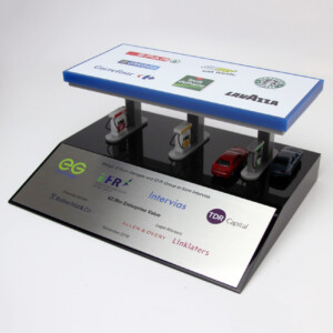 Deal toys of a branded carport with logos of various companies on the roof, featuring miniature cars parked underneath. the base displays sponsor names and investment details.