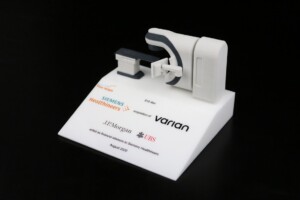 Deal toys of a medical device with company logos from Siemens healthineers, varian, and j.p. Morgan on a display stand.