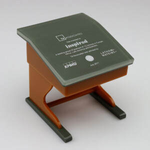 Deal toys, square-shaped and resembling a stool, with a gray top displaying logos and an orange base. text mentions an event for ta associates and kpmg in july 2017.