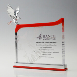 Clear acrylic financial tombstones featuring a silver bird sculpture on top, with a red curved element and printed details about "chance marketing" on the front.