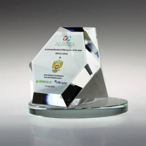 A gleaming, multi-faceted crystal financial tombstone on a glass base, engraved with the logo of alrosa and texts celebrating an award for an association of state universities. the date "11.05.2016" is visible.