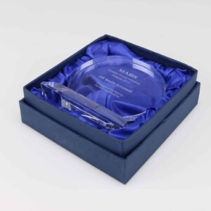 A circular glass financial tombstone engraved with "mars - outstanding innovation - dr. smith project" rests inside an open, square box with a blue satin lining.