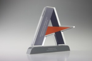 Clear acrylic financial tombstones with a blue and orange star design, inscribed with "renaissance amsterdam hotel, winner hotel awards 2015.” set against a grey gradient background.
