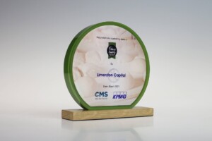 Financial tombstones with a green circular frame standing on a wooden base, featuring text for recognition of corporate acquisition dated march 2021, sponsored by cms and kpmg.