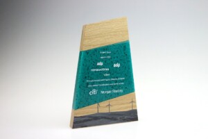 Freestanding triangular financial tombstones with a wood base and a blue-green acrylic body featuring logos of edp renewables, citi, and morgan stanley, and text about a project from march 2021.