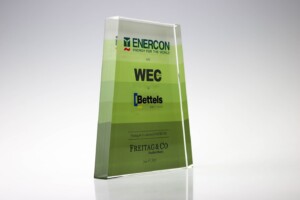 Transparent acrylic financial tombstones with green accents stands on a reflective surface. it features the enercon logo, wec, bettels, and freitag & co inscription, dated june 23, 2017.