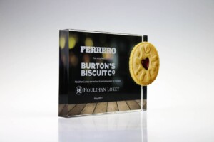 Financial tombstones featuring an announcement that ferrero has acquired burton's biscuit co., with a cookie featuring a heart imprint, and houlihan lokey as the financial advisor, dated may 2021.