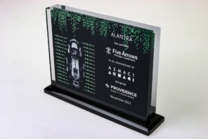 Clear acrylic financial tombstones with a digital green matrix design and text celebrating alantra's investment in five arrows, dated november 2022. the trophy is on a white background.