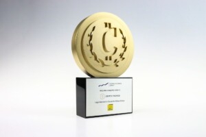 Financial tombstones with a large gold coin featuring a dollar sign at the top, mounted on a black base with an inscription related to a crypto finance award.