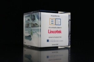 Clear acrylic financial tombstones featuring a label that announces the acquisition of a minority stake in lincotek by the equity club, advised by banca euromobiliare in january 2021. the background is dark.