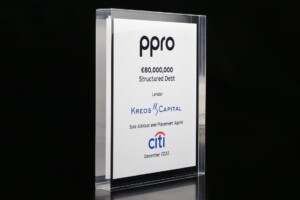 Clear acrylic financial tombstones with black text highlighting a structured debt deal for "ppro" worth €80,000,000, with kreos capital, citi, and december 2022 mentioned.