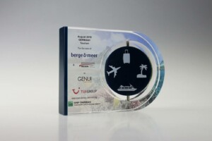 Transparent acrylic financial tombstones with a round central emblem featuring travel-related symbols, presented to berge & meer by the tui group in august 2019, as acknowledged by bnp paribas.