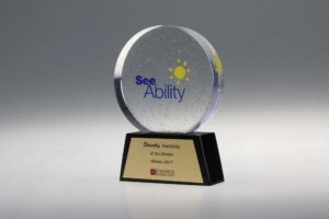 A circular glass recognition award with speckled design and "see ability" logo on top, mounted on a black base with a plaque reading "strictly at the movies winner 2017 by chance uk dancing.